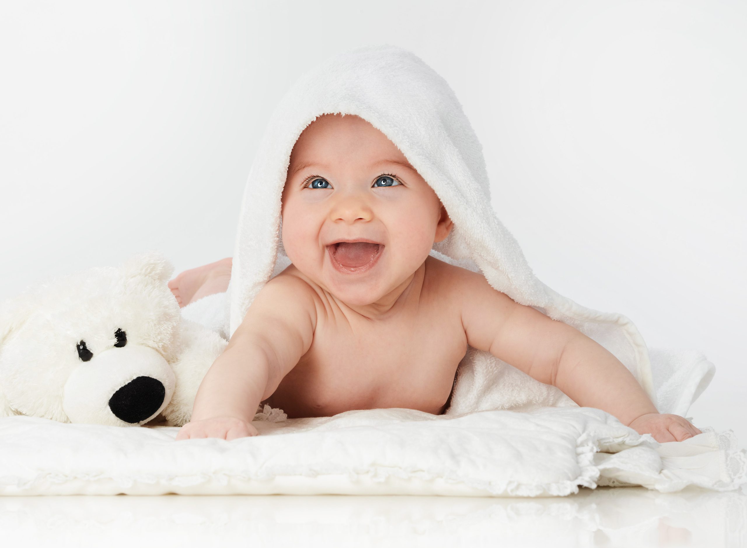 little smiling baby lying under a towel